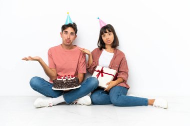 Genç melez bir çift yerde oturmuş doğum gününü kutluyor. Beyaz arka planda izole edilmiş, mutsuz ve hayal kırıklığına uğramış bir şekilde. Çünkü bir şeyi anlamıyorlar.