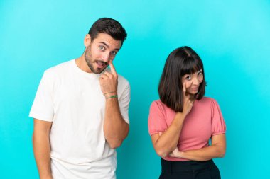 Mavi arka planda izole edilmiş genç bir çift ön tarafa bakıyor.