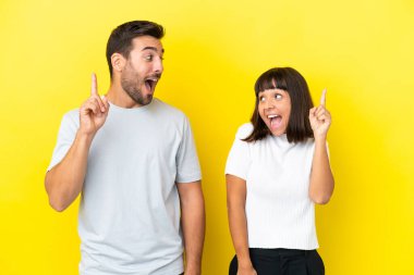 Sarı arka planda izole edilmiş genç bir çift parmak kaldırırken çözümün farkına varmayı amaçlıyor.