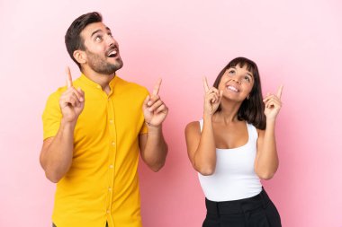 Pembe arka planda izole edilmiş genç bir çift işaret parmağıyla işaret etmek harika bir fikir.