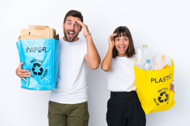 Beyaz arka planda izole edilmiş plastik ve kâğıt dolu bir çantayı tutan genç çift bir şeyin farkına vardı ve çözüme niyetlendiler.