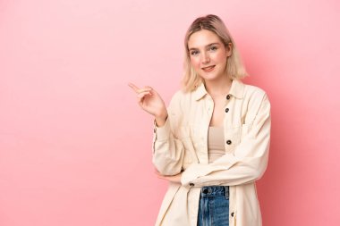 Pembe arka planda izole edilmiş genç beyaz bir kadın.