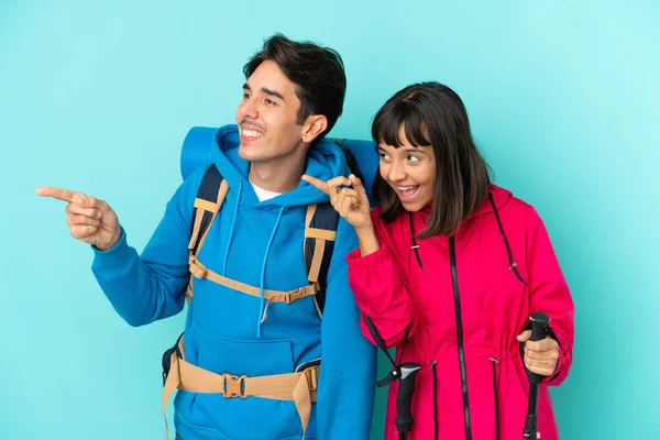 Pareja Jóvenes Montañeros Aislados Sobre Fondo Azul Presentando Una Idea —  Fotos de Stock
