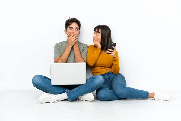 Casal Jovem Com Laptop Móvel Sentado Chão Cobrindo Boca Com — Fotografia de Stock