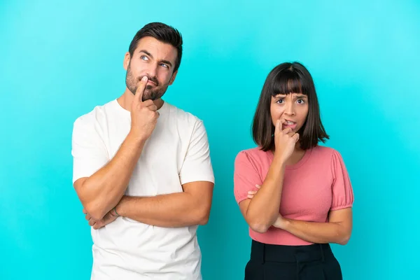 Junges Paar Isoliert Auf Blauem Hintergrund Mit Zweifeln Beim Nachschauen — Stockfoto