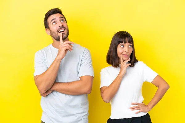Junges Paar Isoliert Auf Gelbem Hintergrund Beim Nachdenken Über Eine — Stockfoto