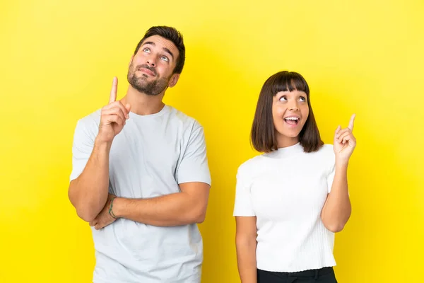 Jong Paar Geïsoleerd Gele Achtergrond Wijzend Een Geweldig Idee Zoek — Stockfoto