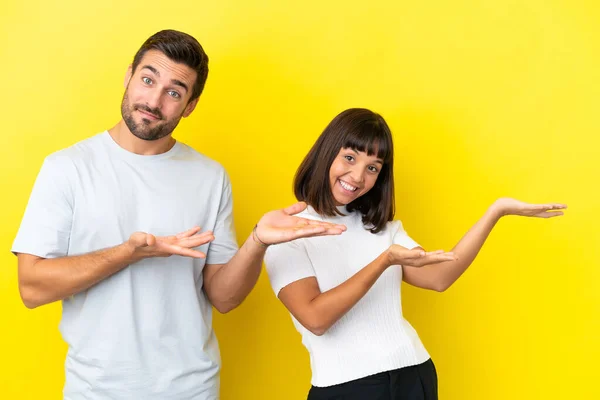 Pasangan Muda Terisolasi Latar Belakang Kuning Memperpanjang Tangan Sisi Untuk — Stok Foto