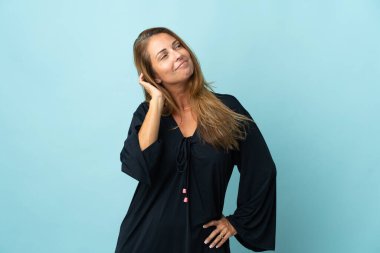 Orta yaşlı Brezilyalı kadın, mavi arka planda izole edilmiş bir şekilde bir fikir düşünüyor.