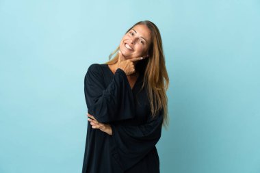 Orta yaşlı Brezilyalı kadın mavi arka planda izole edilmiş, gülümsüyor.