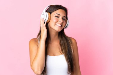 Pembe arka planda izole edilmiş genç Brezilyalı kız müzik dinliyor.