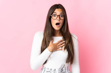 Pembe arka planda izole edilmiş genç Brezilyalı kadın şaşırdı ve şaşırdı.