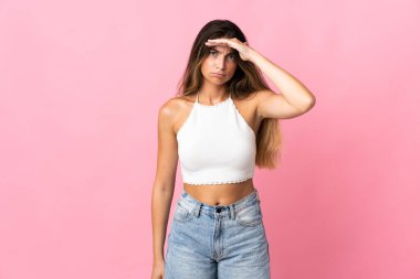 Pembe arka planda soyutlanmış beyaz bir kadın. Bir şeye bakmak için uzaklara bakıyor.