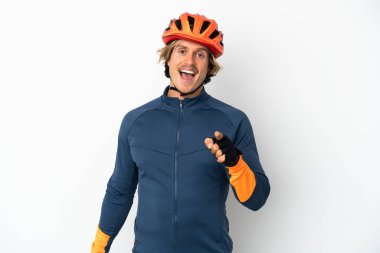 Beyaz arka planda izole edilmiş genç sarışın bisikletçi şaşırmış ve ön tarafı işaret ediyor.