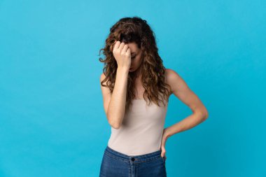 Kafkasyalı genç bir kadın mavi arka planda izole edilmiş, baş ağrısı var.