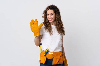 Genç elektrikçi beyaz arka planda izole edilmiş mutlu bir ifadeyle selamlıyor.