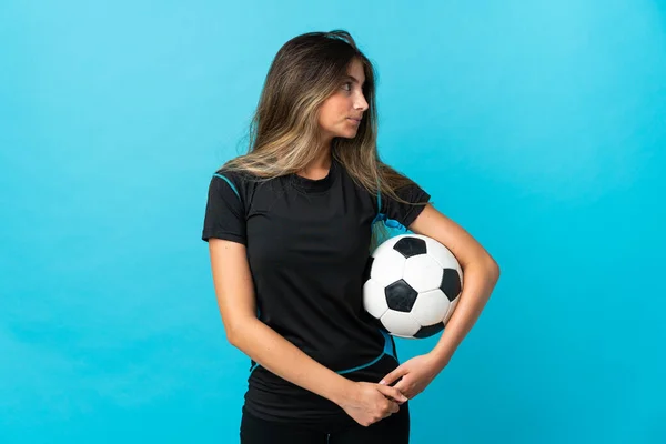 Młody Piłkarz Kobieta Odizolowany Niebieskim Tle Patrząc Bok — Zdjęcie stockowe