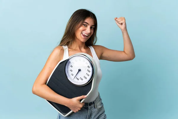 Jonge Blanke Vrouw Geïsoleerd Blauwe Achtergrond Houden Van Een Weegmachine — Stockfoto