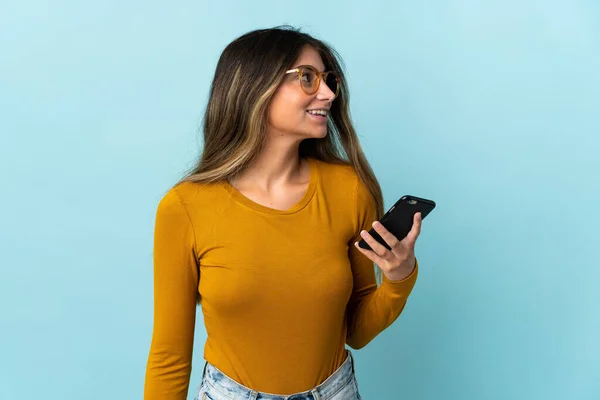 Giovane Donna Caucasica Utilizzando Telefono Cellulare Isolato Sfondo Blu Guardando — Foto Stock