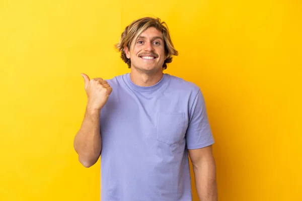 Pohledné Blondýny Muž Izolované Žlutém Pozadí Ukazuje Stranu Prezentovat Produkt — Stock fotografie