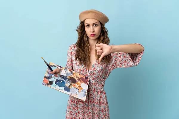 Ung Konstnär Flicka Håller Palett Isolerad Blå Bakgrund Visar Tummen — Stockfoto