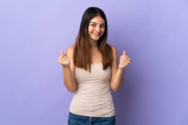 Mor arka planda izole genç beyaz kadın para hareketi yapıyor.