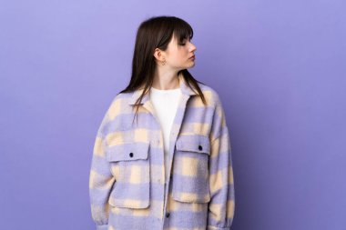 Mor arka planda izole edilmiş genç Ukraynalı kadın yan tarafa bakıyor.