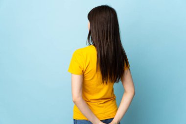 Genç Ukraynalı kız mavi arka planda izole edilmiş ve geriye bakıyor.