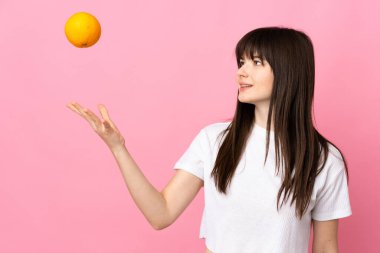 Pembe arka planda izole edilmiş genç Ukraynalı kadın elinde bir portakal tutuyor.