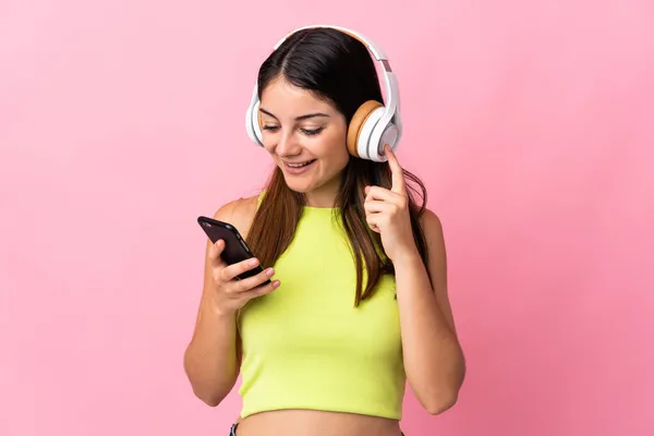 Joven Mujer Caucásica Aislada Sobre Fondo Rosa Escuchando Música Con —  Fotos de Stock