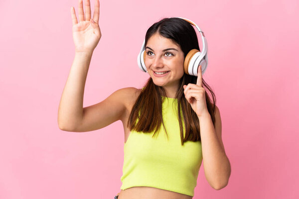 Young caucasian woman isolated on pink background listening music and dancing