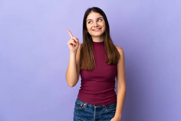 指を持ち上げながら解決策を実現しようと紫色の背景に隔離された若い白人女性 — ストック写真