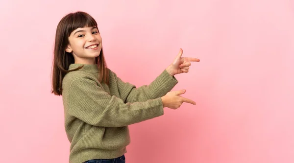 Liten Flicka Isolerad Rosa Bakgrund Peka Finger Sidan Och Presentera — Stockfoto