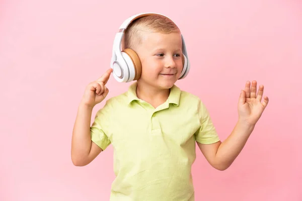 被粉色背景隔离的俄罗斯小男孩 一边听音乐一边唱歌 — 图库照片