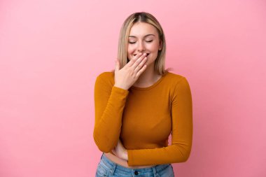 Pembe arka planda izole edilmiş genç beyaz kadın mutlu ve gülümsüyor.