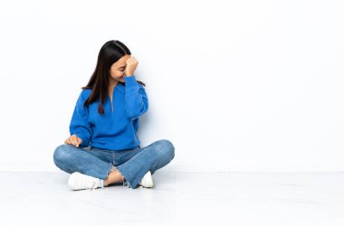 Genç melez kadın beyaz arka planda yapayalnız oturmuş gülüyor.