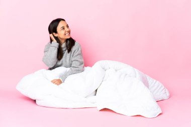 Genç melez kadın pijama giymiş yerde oturmuş bir fikir düşünüyor.