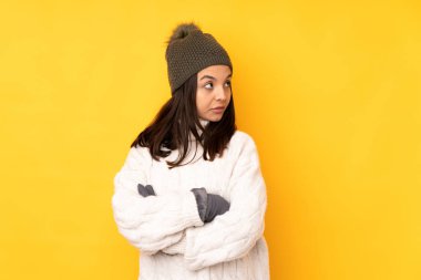 İzole edilmiş sarı arkaplan portresi üzerinde kışlık şapkalı genç bir kadın.