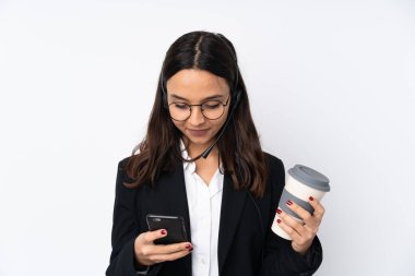 Genç pazarlamacı kadın beyaz arka planda izole edilmiş. Elinde kahve ve cep telefonu var.