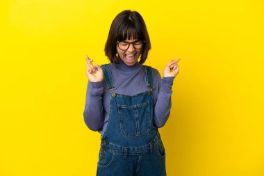 İzole edilmiş sarı arka planda genç hamile bir kadın.