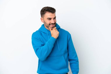 Beyaz arka planda izole edilmiş genç beyaz adam yana bakıyor ve gülümsüyor.