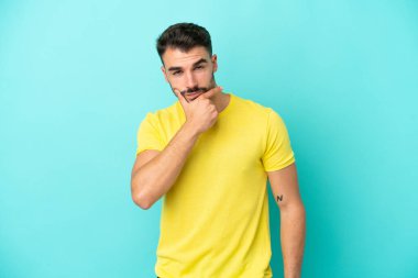 Kafkasyalı genç adam mavi arka planda soyutlanmış düşünüyor.