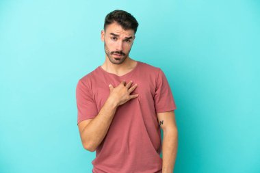 Mavi arka planda izole edilmiş genç beyaz adam kendini işaret ediyor.