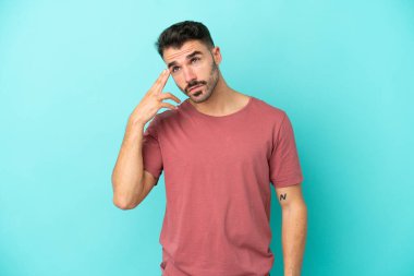 Genç beyaz adam mavi arka planda izole edilmiş ve intihar jesti yapmada sorun yaşıyor.