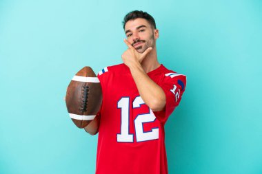 Rugby oynayan genç beyaz adam mavi arka planda izole edilmiş mutlu ve gülümsüyor.