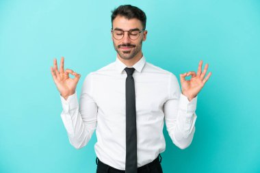 Beyaz iş adamı Zen pozunda mavi arka planda izole edilmiş.