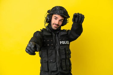 Özel Tim 'in beyaz adamı sarı arka planda izole edilmiş. Gülümserken parmaklarını sana gösteriyor.
