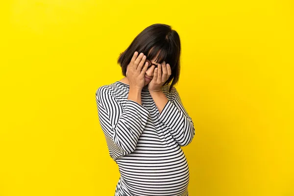 若いです妊婦上の隔離された黄色の背景カバー目によって手 — ストック写真