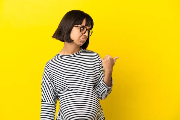 Jovem Grávida Sobre Fundo Amarelo Isolado Infeliz Apontando Para Lado — Fotografia de Stock