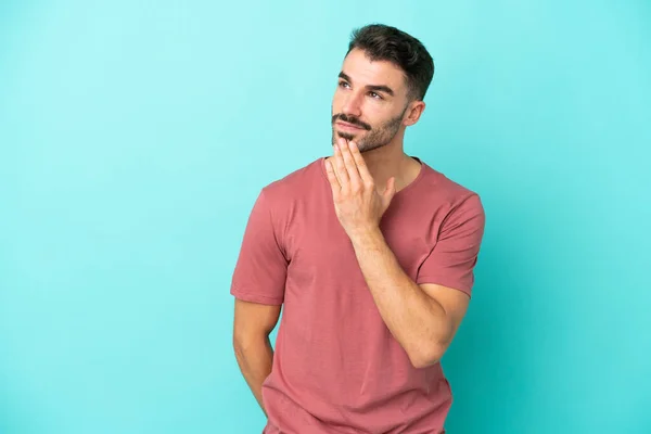 Jonge Kaukasische Man Geïsoleerd Blauwe Achtergrond Zoek Omhoog Terwijl Glimlachen — Stockfoto